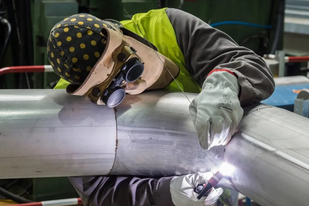 Lasser werkt een lasverbinding aan een stalen leiding af